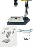 Tafelboormachine, handleiding, sleutels en koolborstels op witte achtergrond.