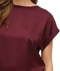 Detail van de schouder en korte, omgeslagen mouw van een bordeauxrood satijnen blouse.