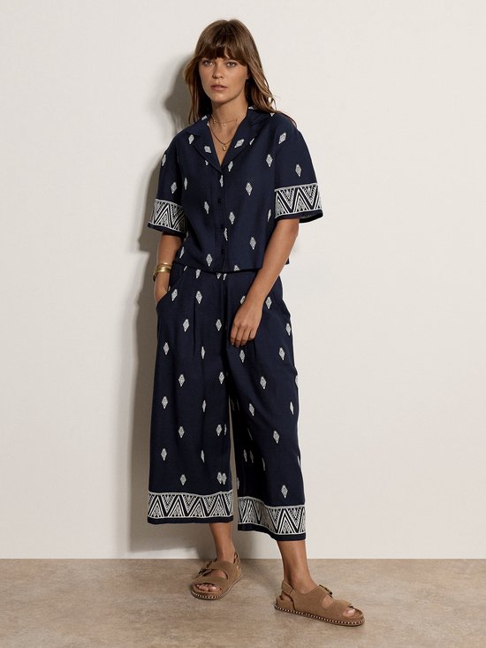 Model in marineblauwe culotte met witte diamantjes en geborduurde randen. Kort shirt met dezelfde print.