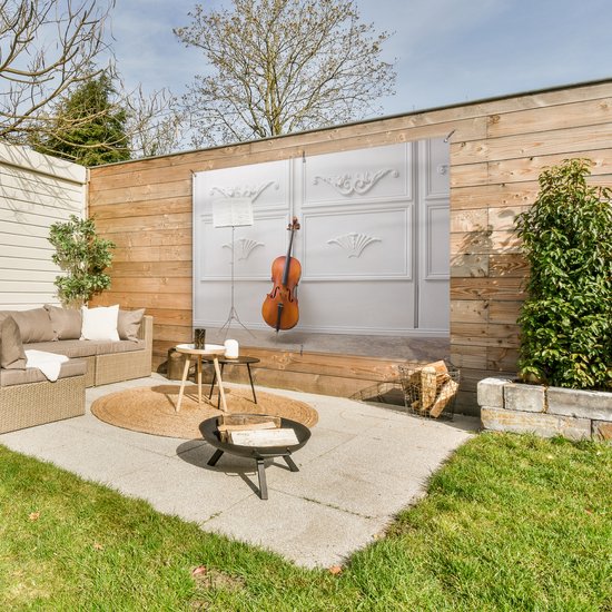 Tuinposter 180x120 cm - Tuindecoratie Een cello tegen een witte muur - Poster voor in de tuin - Buiten decoratie - Schutting tuinschilderij - Tuindoek muurdecoratie - Wanddecoratie balkondoek
