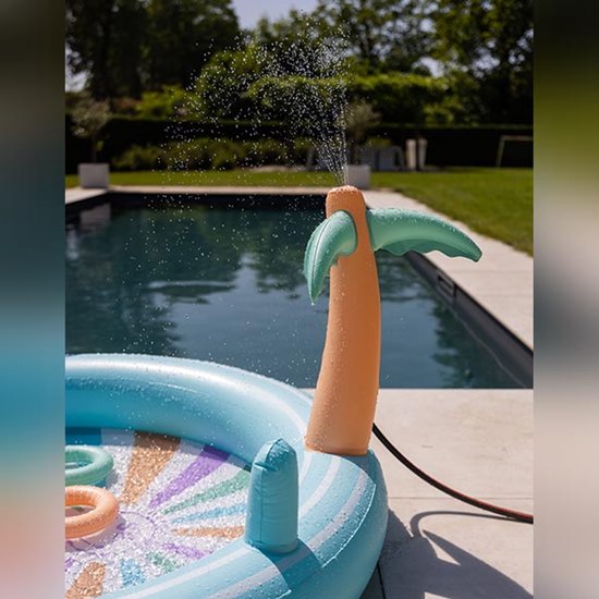 Palmtak sproeier van een opblaasbaar zwembad sproeit water. De bodem van het zwembad heeft een zonnespatroon.