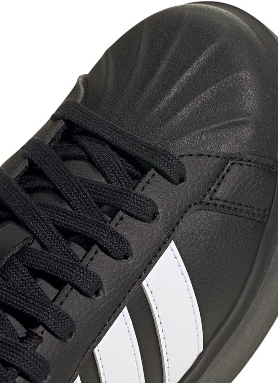 Detail van de neus van een zwarte damessneaker met veters en witte Adidas-strepen.