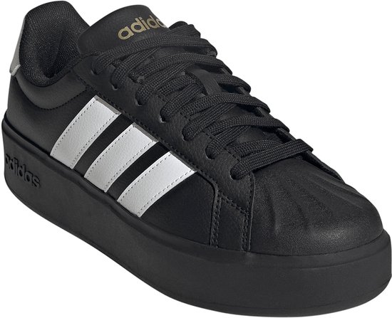 Zwarte damessneaker met dikke zool, witte Adidas-strepen op de zijkant en gouden details.