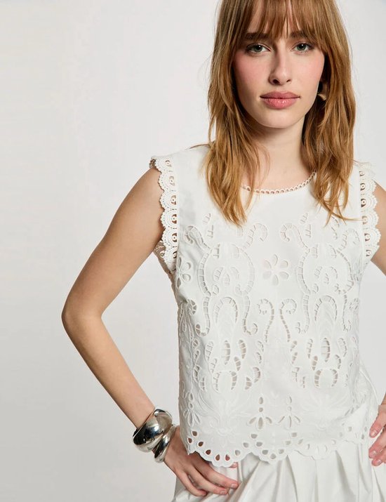 Close-up van een model in een witte kanten top met kanten details.