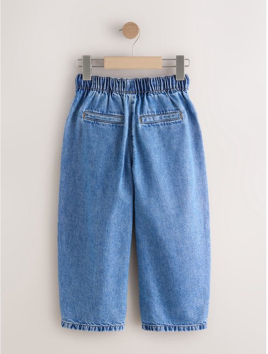 Achterkant van wijde, ronde jeans met elastische tailleband en twee paspelzakken, in denim.