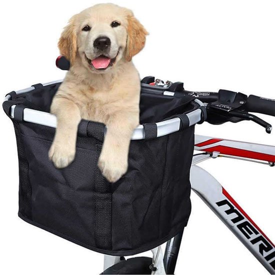 Een vrolijke puppy zit in een zwarte stoffen fietsmand op een fiets.