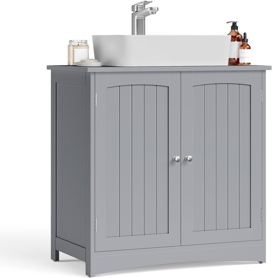 Grijze badmeubel met twee deuren, met wastafel en kraan erboven, en enkele flessen.