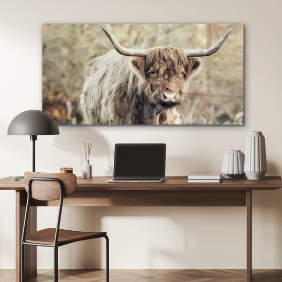 Werkkamer met een Schotse Hooglander glasschilderij boven een bureau met laptop.