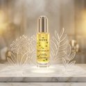 Nuxe Super Serum [10] anti-age serum in glazen flesje met gouden dop, omringd door decoratieve bladeren.