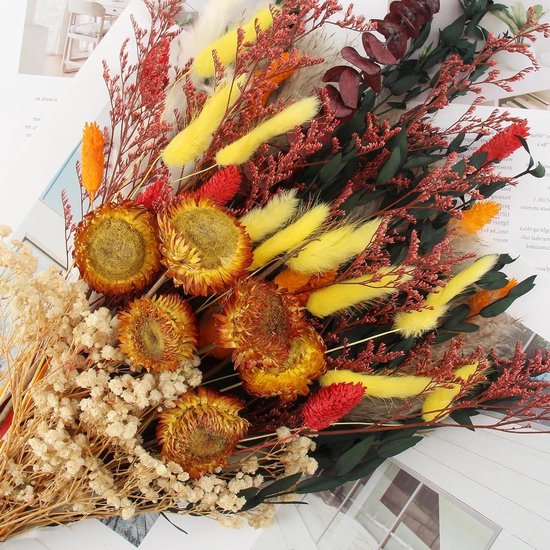 Close-up van een boeket met oranje zonnebloemen, geel pampasgras en rode takken.