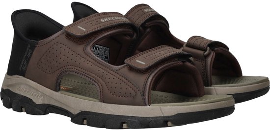 Paar bruine Skechers Slip-Ins sandalen met klittenbandsluiting en rubberen zool.
