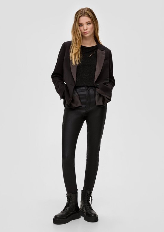 Model in zwarte gecoate broek, zwarte blazer, glittertop en veterlaarzen met grove zool.