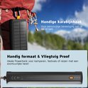 Zwarte Xtorm powerbank met zonnepaneel en karabijnhaak, bevestigd aan een rugzak.