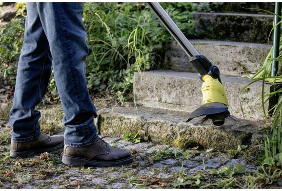 Man in spijkerbroek gebruikt de gele en zwarte voegenborstel op stenen trappen.
