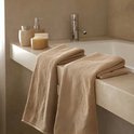 Deux serviettes beiges pliées sur un lavabo en marbre à côté de distributeurs de savon.