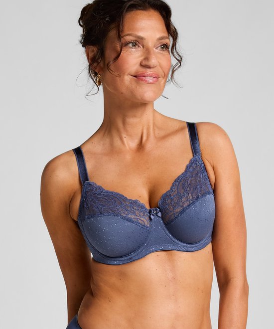 Blauwe beugelbh met stippenpatroon en kanten bovenkant van de cups, gedragen door een model.