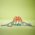 Brug van oranje en grijze blokken, met groene en beige steunen. Spoorrails en kleine figuren.