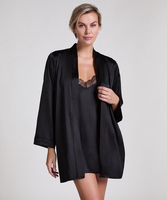 Model in zwarte satijnen kimono met kanten afwerking op de overslag en strik.