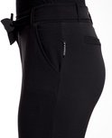 Detail van de tailleband met strikceintuur van een zwarte broek. Het merk 'JE M'APPELLE' is zichtbaar.