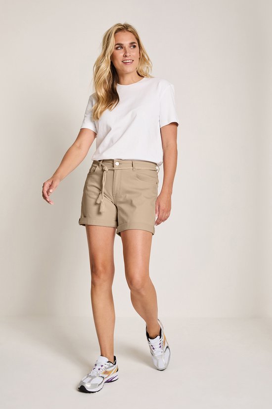 Model draagt een bruine chino short met touwceintuur en opgerolde broekspijpen, gecombineerd met een witte top.