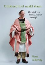 Man met lang, grijs haar in een staartje. Draagt een roze priesterkleed met groene en zwarte details en kwastjes.