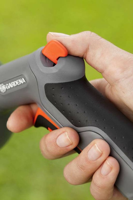 Close-up van een hand die de oranje trigger van een grijze Gardena sproeikop indrukt.