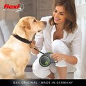 Vrolijke vrouw met gele Labrador, beide kijken elkaar aan. Vrouw houdt een zwarte Flexi rolriem vast.