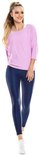 Model in lichtpaarse top met driekwart mouwen en navy legging, met witte sneakers.