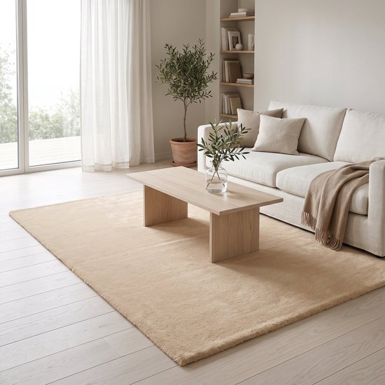 Beige hoogpolig vloerkleed in een woonkamer, onder een houten salontafel met bank.