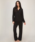 Model in volledige zwarte jersey pyjamaset met kraag, knoopsluiting en wijde broek.