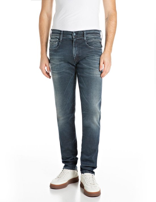Model in donkerblauwe Replay jeans met een slanke snit, gecombineerd met witte sneakers.