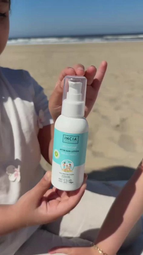 Kind houdt een witte fles met lichtblauwe label vast. 'INCIA 100% NATURAL AFTER SUN LOTION FOR ALL FAMILY' en tekening van een gezin op het strand.
