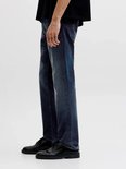 Detail van een man in blauwe jeans en zwarte schoenen.