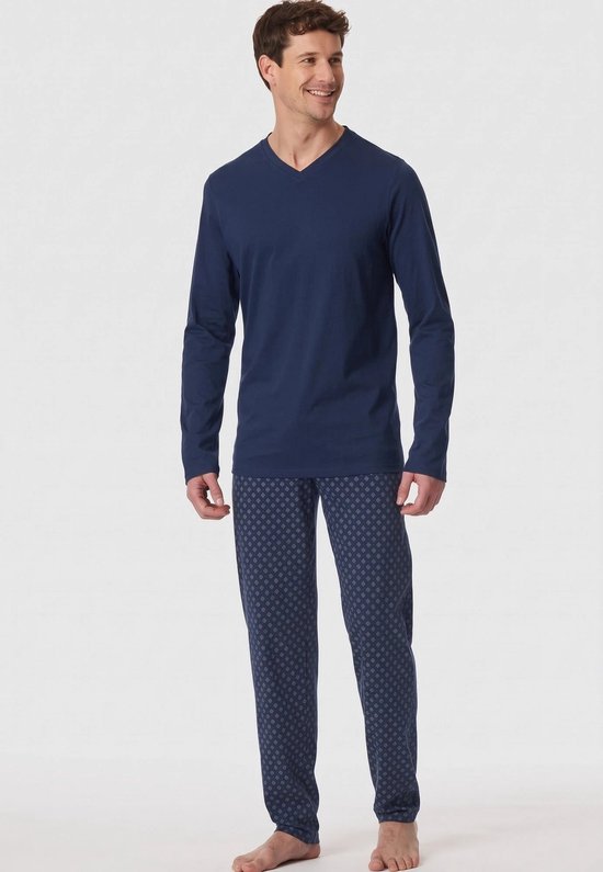 Man met lange mouwen marineblauw V-hals pyjamashirt en een pyjamabroek met een grafisch patroon in donkerblauw en lichtblauw.