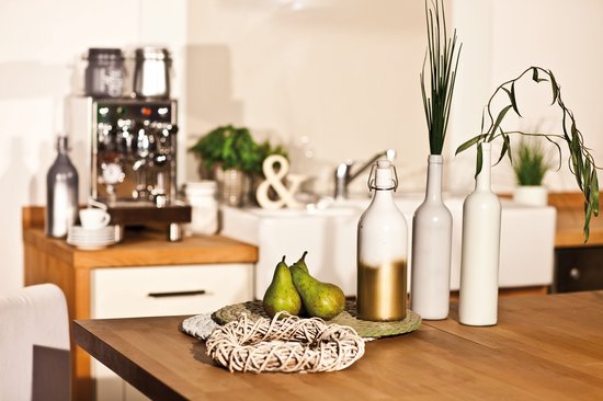 Twee groene peren op een ronde mat voor twee witte vazen en een gouden fles.