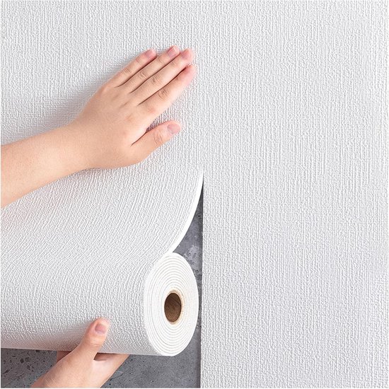 Mains appliquant un rouleau de papier peint texturé blanc auto-adhésif sur un mur.