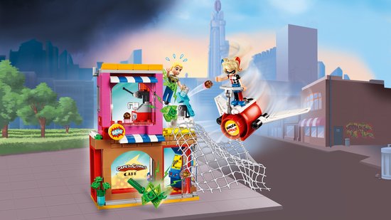 LEGO-actiescène: twee meisjes op een jetpack vallen een roze met bruin gebouw aan, met netten en groene kristallen.