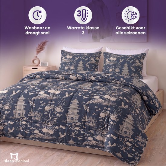 Een opgemaakt bed met een blauw dekbed en kussens met pagode-, bloemen- en vogelprint.