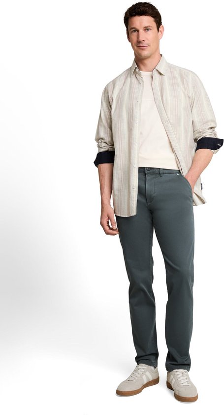 Man in een beige T-shirt, gestreepte blouse en donkergroene chino broek.