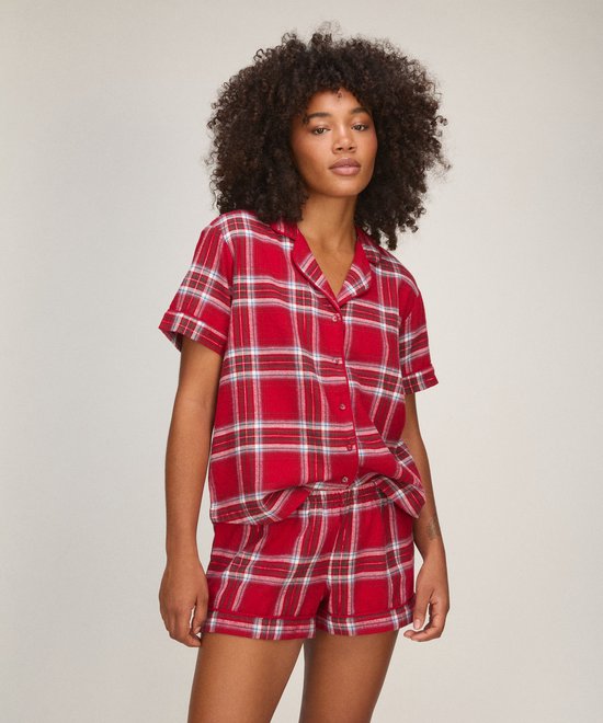 Model in een rode pyjamaset met ruitpatroon, bestaande uit een top met korte mouwen en een short.