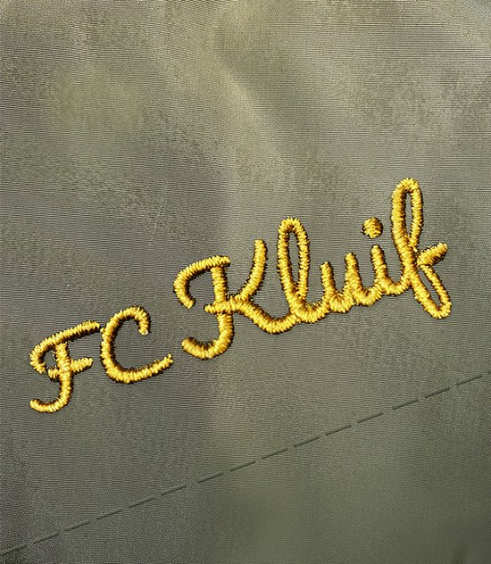 Detail van geborduurd logo 'FC Kluif' in goudkleurige letters op groen jack.