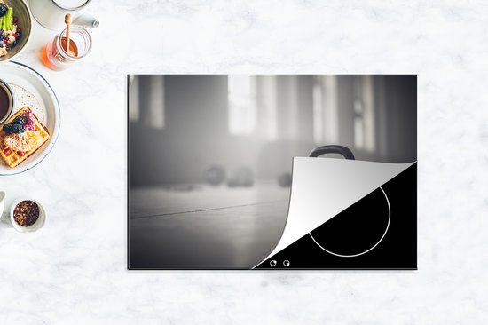 KitchenYeah® Inductie beschermer 76x51.5 cm - Verschillende kettlebellgewichten op de vloer in een fitnessruimte - Kookplaataccessoires - Afdekplaat voor kookplaat - Inductiebeschermer - Inductiemat - Inductieplaat mat