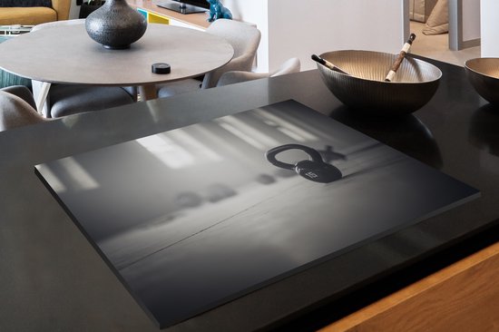 KitchenYeah® Inductie beschermer 76x51.5 cm - Verschillende kettlebellgewichten op de vloer in een fitnessruimte - Kookplaataccessoires - Afdekplaat voor kookplaat - Inductiebeschermer - Inductiemat - Inductieplaat mat