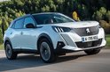 Witte Peugeot 2008 SUV in beweging op een weg, met bomen op de achtergrond.