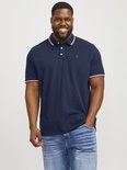 Man met een donkerblauwe polo met rode en witte strepen aan kraag en mouwen, lachend.