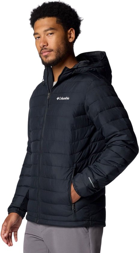 Man in zwarte Columbia gewatteerde jas met capuchon, vest met rits en grijze broek.