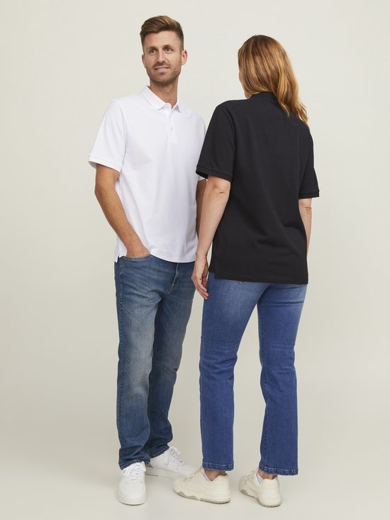 Man in wit poloshirt en vrouw in zwart poloshirt, staand naast elkaar, denim jeans.