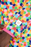 Close-up van de mouw van een kleurrijk confettipak, met een OppoSuits label en blauwe knopen.