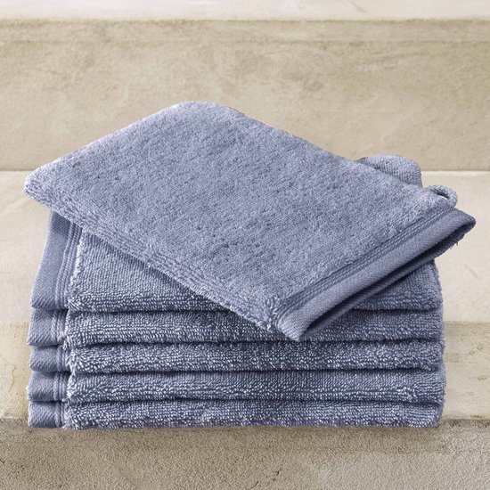 Stapel stone blue washandjes met een zichtbare lus, op een stenen achtergrond.