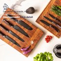 Koksmes met damascus patroon en donker handvat op een houten plank met ingrediënten.